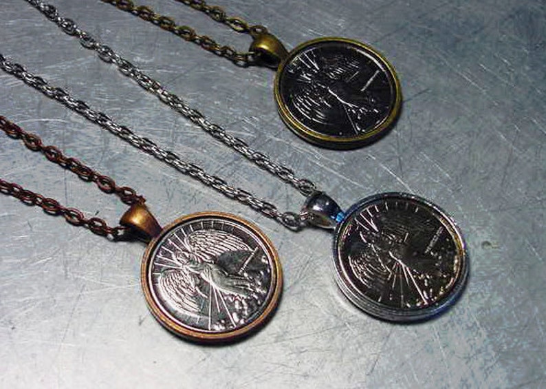 May include: Three silver necklaces with round pendants featuring an angel design. The pendants have a silver finish and are attached to silver chains.
