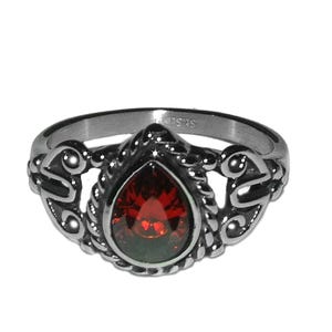 May include: A silver ring with an ornate design featuring a teardrop-shaped red gemstone.