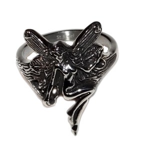 May include: A silver ring with a detailed fairy design. The fairy is sitting on a branch with her wings spread out. The ring is marked "St. Steel".