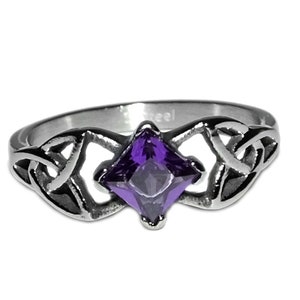 May include: A silver-colored ring with a square, purple gemstone at the center. The ring features a Celtic knot design on either side of the gemstone. The word "Steel" is visible on the ring.