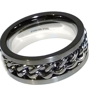 May include: A silver stainless steel ring with a braided design. The ring is wide and has a polished finish.
