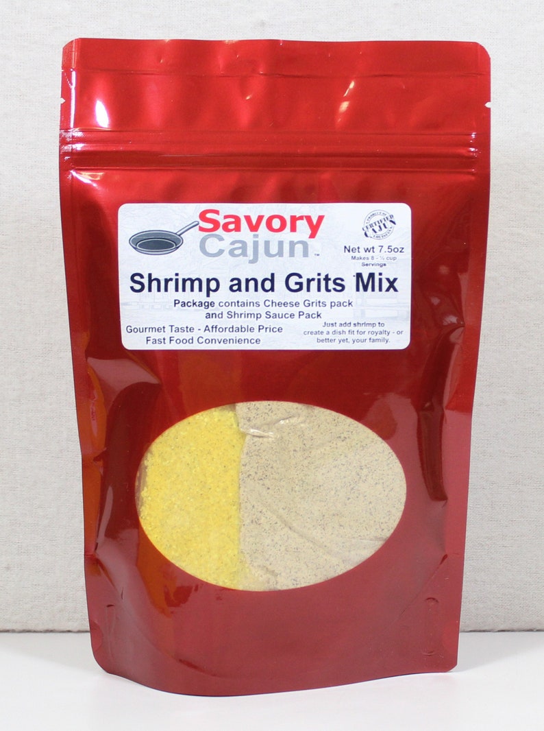May include: Red resealable pouch with a clear window showing yellow and gray grits mix. The pouch has a white label with the text "Savory Cajun. Shrimp and Grits Mix" and "Net wt 7.5oz".