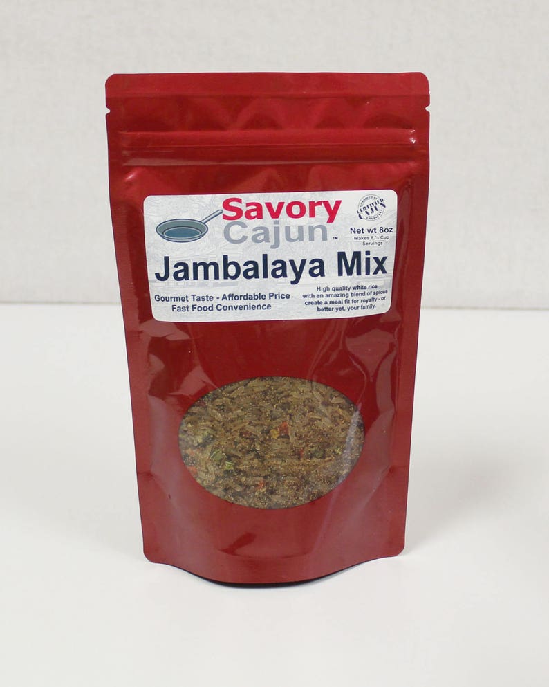 May include: Red resealable pouch with a clear window showing a brown spice blend. The label reads "Savory Cajun Jambalaya Mix" with the tagline "Gourmet Taste - Affordable Price Fast Food Convenience". The label also states "Net wt 8oz (Makes 6 - 8 Cups Servings)".
