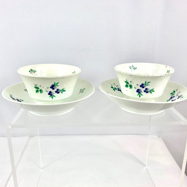 Soft paste porcelain handleless tea sipper cups and cooling bowls, painted with blue forget me nots. Matched pair, 18th century