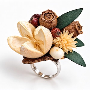 May include: A ring featuring a large, light beige dried seed pod, a small pale yellow flower, dark red berries, brown textured seed capsules, and dark green leaves attached to a smooth, polished silver-toned metal band.