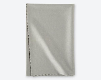 May include: A rectangular light gray microfiber cleaning cloth with a fine, uniform woven texture and distinct zigzag pinked edges along the vertical side, designed for wiping surfaces clean without leaving any residue or lint behind.