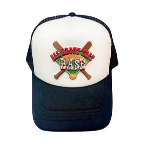 May include: A baseball cap with a white front panel and a black brim and mesh back. The front features the text "ALL ABOUT THAT BASE" in red, green, and tan, with crossed baseball bats.