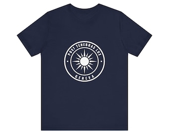 May include: A navy blue short-sleeve t-shirt featuring a white circular emblem on the chest. The emblem contains a central sunburst design surrounded by the text POST TENEBRAS LUX and GENEVA in a clean, sans-serif capital font.