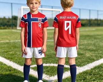 May include: A red soccer jersey with a blue and white cross pattern, the number 9, and a crest on the front. The back features the name BRAUT HAALAND and the number 9. Paired with white shorts, dark blue socks, and white sneakers.