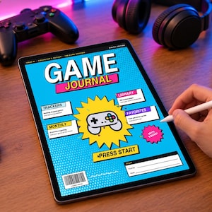 May include: A digital tablet displaying a Game Journal interface with a bright blue background, a central game controller graphic, and sections labeled Trackers, Library, Favorites, Monthly, and Press Start, featuring comic-book style text and graphics.