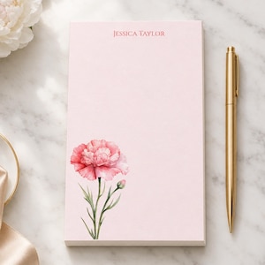 May include: A rectangular light pink notepad featuring a watercolor illustration of a pink carnation flower with green stems and leaves at the bottom, and the name JESSICA TAYLOR printed in dark pink text at the top center.