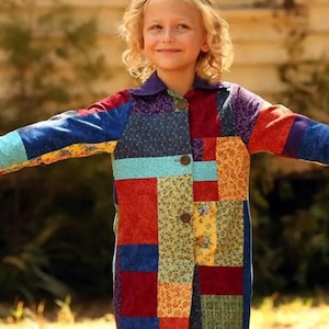 Può includere: Un cappotto a maniche lunghe caratterizzato da un design patchwork composto da vari pezzi di tessuto rettangolari in tonalità di rosso, blu, giallo e verde con motivi floreali e geometrici. Il cappotto ha un colletto viola a tinta unita e tre bottoni.