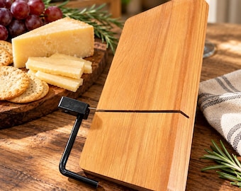 May include: A rectangular wooden cheese slicer featuring a light brown grain pattern and a black metal handle with a thin wire cutter that extends across the surface of the board to slice through blocks of cheese with precision.