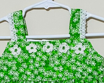 Green dress for aToddler in a nice pattern design fabric with white handmade crocheted flowers.