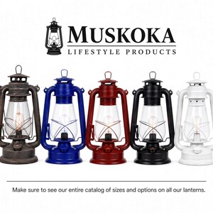 Pu&ograve; includere: Cinque lanterne da tempesta in bronzo, blu, rosso, nero e bianco, ciascuna con un globo di vetro trasparente e una lampadina interna. Il testo MUSKOKA LIFESTYLE PRODUCTS appare sopra, e il testo Make sure to see our entire catalog of sizes and options on all our lanterns appare sotto.