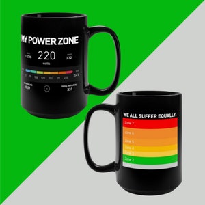 May include: Two black coffee mugs. One mug features a power zone chart with the text "MY POWER ZONE" and "220 watts". The other mug features a colorful chart with the text "WE ALL SUFFER EQUALLY."