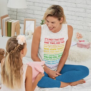K&ouml;nnte beinhalten: Eine Frau tr&auml;gt ein graues Tanktop mit einem bunten Text-Motiv, auf dem "It's not that deep... One Two. One Two... Wig Awn Tight!" steht. Sie sitzt auf einem Bett mit einem jungen M&auml;dchen. Die Frau l&auml;chelt und schaut das M&auml;dchen an. Das M&auml;dchen h&auml;lt ein rosa geh&auml;keltes Spielzeug in der Hand.