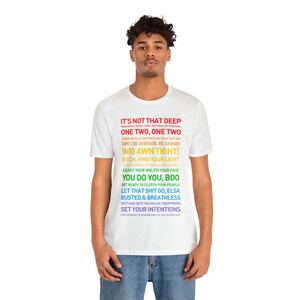 K&ouml;nnte beinhalten: Wei&szlig;es T-Shirt mit einem bunten Grafikdruck mit dem Text "It's not that deep", "One two, one two", "Wig awn tight!" und mehr.