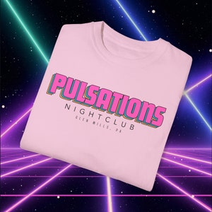 May include: Pink t-shirt with the text "Pulsations Nightclub Glen Mills, PA" in a retro, multi-colored font.