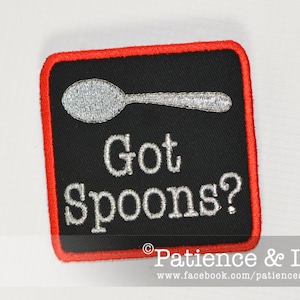 Peut inclure: Un patch carré noir avec une bordure rouge. Le patch a une cuillère brodée argentée et le texte "Got Spoons?" en broderie argentée. Le bas du patch a le texte "Patience & Love" en broderie blanche.