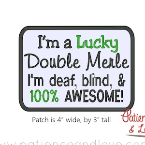 Op de afbeelding: Een wit en blauw geborduurde patch met zwarte tekst die "I'm a Lucky Double Merle I'm deaf, blind, & 100% AWESOME!" luidt. De patch is 10 cm breed en 7,5 cm hoog.