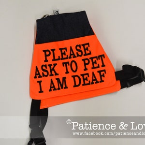 May include: Orange safety vest with black straps and the text "PLEASE ASK TO PET I AM DEAF".