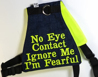 Könnte beinhalten: Ein blaues Jeans- und neongelbes Hundegeschirr mit dem aufgestickten Text "No Eye Contact Ignore Me I'm Fearful" auf der Vorderseite.