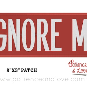 Puede incluir: Parche rectangular rojo con texto blanco que dice "IGNORE ME". El parche mide 8 pulgadas por 3 pulgadas.