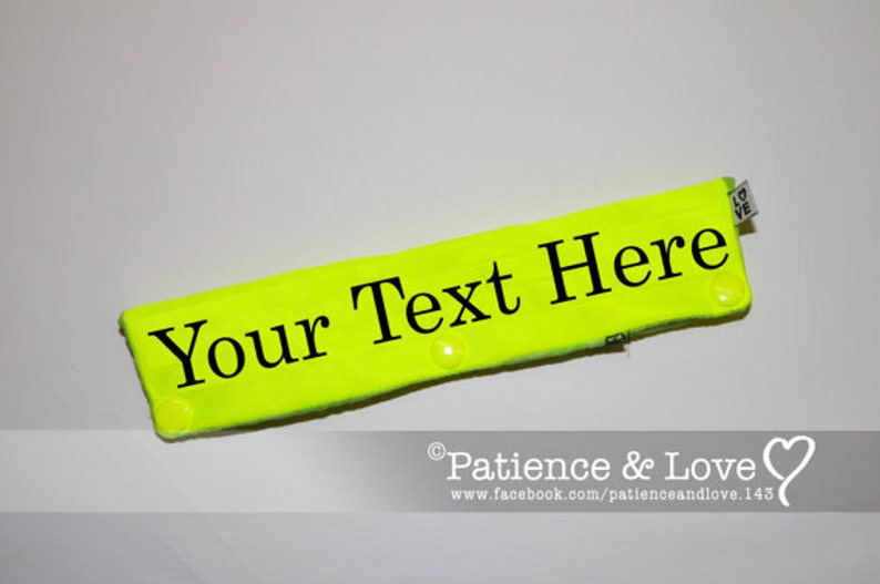 以下が含まれることがあります： 「Your Text Here」という黒い文字が書かれた明るい黄色のヘッドバンド。ヘッドバンドには、「Love」と書かれた小さな白いタグが付いています。