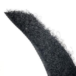 Puede incluir: Primer plano de una cinta de velcro negra. El lado peludo de la cinta es visible, mostrando las fibras individuales.