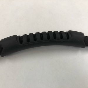 Può includere: Maniglia in gomma nera con impugnatura testurizzata, fissata a un cinturino in nylon nero.