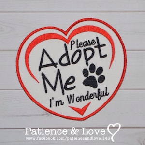 Könnte beinhalten: Weißer herzförmiger Patch mit roten Nähten und dem Text "Please Adopt Me I'm Wonderful" in Schwarz. Ein schwarzer Pfotenabdruck befindet sich neben dem Wort "Me".