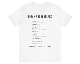 May include: A white short-sleeved t-shirt featuring the text SPEAK RHODE ISLAND in dark blue. Below, a list of local terms and definitions includes cabinet, bubbler, grindah, packy, wicked, the bridge, and locals summer, ending with NEWPORT - AQUIDNECK ISLAND.