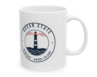 May include: A white ceramic mug featuring a circular navy blue graphic. The design depicts a lighthouse with a red light beam, set above stylized waves. The text reads OCEAN STATE around the top and NEWPORT RHODE ISLAND at the bottom.