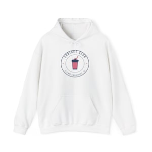 Może przedstawiać: Biała bluza z kapturem i długimi rękawami z okrągłą grafiką na piersi. Logo przedstawia różowy napój w ciemnoniebieskim kubku ze słomką, otoczony napisem CABINET CLUB oraz IT'S NOT A MILKSHAKE.