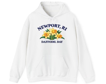 Peut inclure: Un sweat-shirt à capuche blanc avec un motif de trois jonquilles jaunes et des feuilles vertes. Le texte au-dessus des fleurs indique NEWPORT, RI et le texte en dessous indique DAFFODIL DAY en lettres capitales bleu foncé.