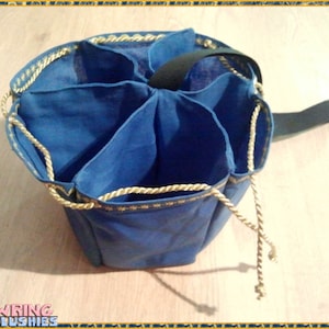 Könnte beinhalten: Eine blaue Stofftasche mit sechs Fächern und goldenen Seilgriffen. Die Tasche hat einen schwarzen Riemen.