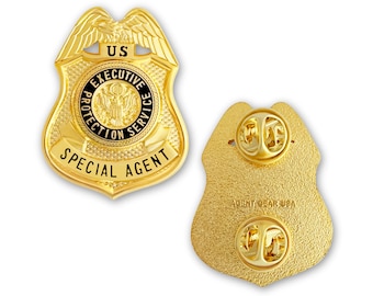 May include: Gold-colored metal badge with the words "US Executive Protection Service Special Agent" on the front and a pin on the back.