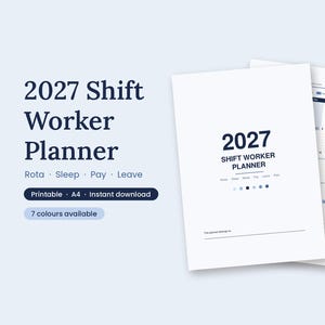 May include: A 2027 shift worker planner with a white cover featuring dark blue text that reads 2027 Shift Worker Planner, Rota, Sleep, Pay, Leave. A tan pen rests on the open planner pages showing a monthly calendar grid layout.