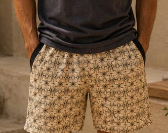 May include: A charcoal gray short-sleeved t-shirt with a chest pocket and a silver chain necklace paired with beige shorts featuring a repeating dark brown geometric star pattern and dark side panels at the waistline.
