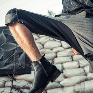 May include: A black leather ankle boot featuring a side zipper closure, a rounded toe, and a low stacked heel. The boot is constructed with smooth leather panels and a visible vertical metal zipper on the outer side, extending from the ankle collar.
