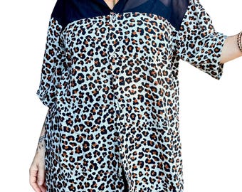 Op de afbeelding: Een button-down shirt met een luipaardprint. De blouse heeft een zwarte kraag en schouderstuk, met doorschijnende zwarte stof op de bovenborst en mouwen. De luipaardprint is bruin en zwart op een witte achtergrond.