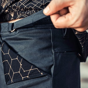 May include: Dark gray pants with a black geometric pattern pocket and a black belt with a silver buckle.