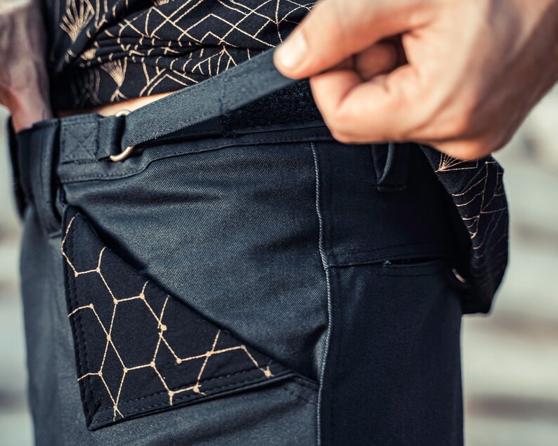 May include: Dark gray pants with a black geometric pattern pocket and a black belt with a silver buckle.