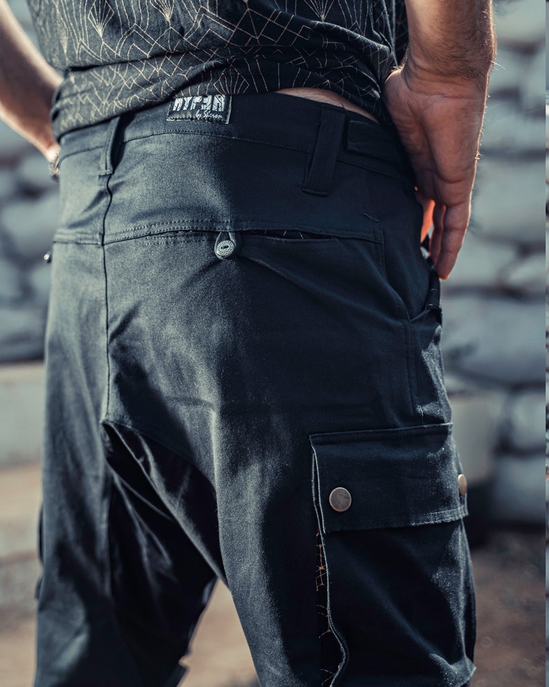 May include: Black cargo pants with a large pocket on the right leg. The pants have a belt loop and a small pocket on the back. The pants have a label that says "WTF" on the back.