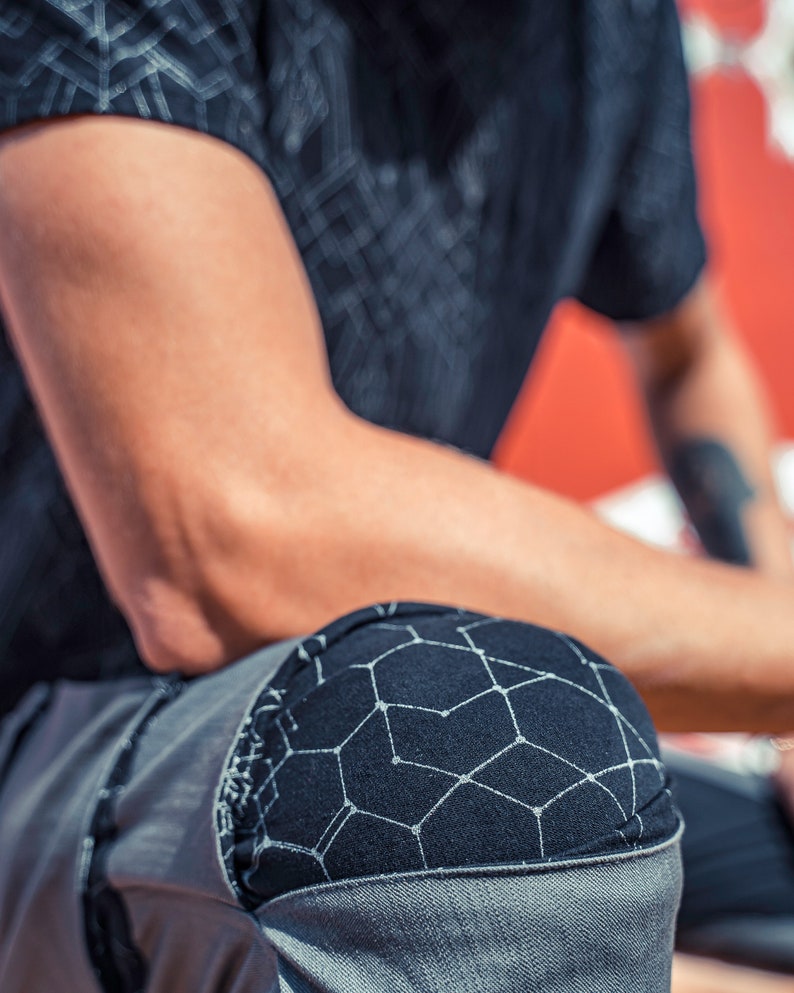 May include: A black short-sleeved shirt and grey pants featuring a black knee patch with a white geometric constellation-like pattern. The shirt also displays a matching white geometric pattern across the fabric, creating a cohesive look.