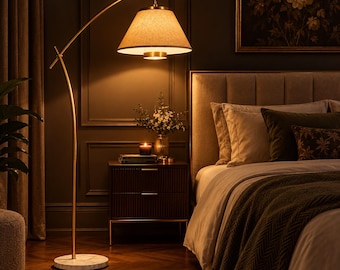 May include: A tall, arched floor lamp with a brushed gold metal frame and a circular white marble base. The lamp features a wide, conical fabric shade that emits a warm, downward-facing glow, illuminating the surrounding space.