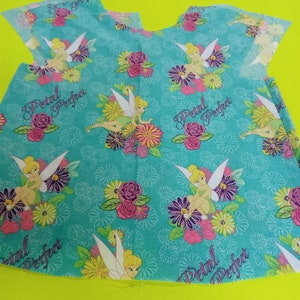 May include: A turquoise fabric piece featuring a floral and fairy design. The fabric has a repeating pattern of fairies, flowers, and the text "Petal Perfect". The flowers are in shades of pink, yellow, and purple.
