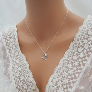 Puede incluir: Un collar de cadena de plata con un peque&ntilde;o dije de perla y un dije de estrella de mar de plata.