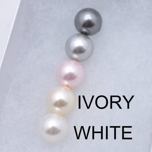Puede incluir: Cinco perlas en fila, de izquierda a derecha: gris, plata, rosa claro, marfil y blanco. El texto "IVORY" y "WHITE" est&aacute; escrito debajo de las perlas.